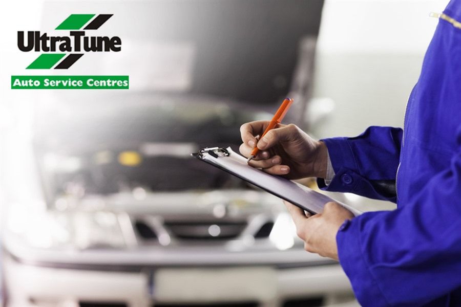 A Man is Writing on a Clipboard in Front of an Ultra Tune Auto Service Centre — Ultra Tune Nambour In Nambour, QLD