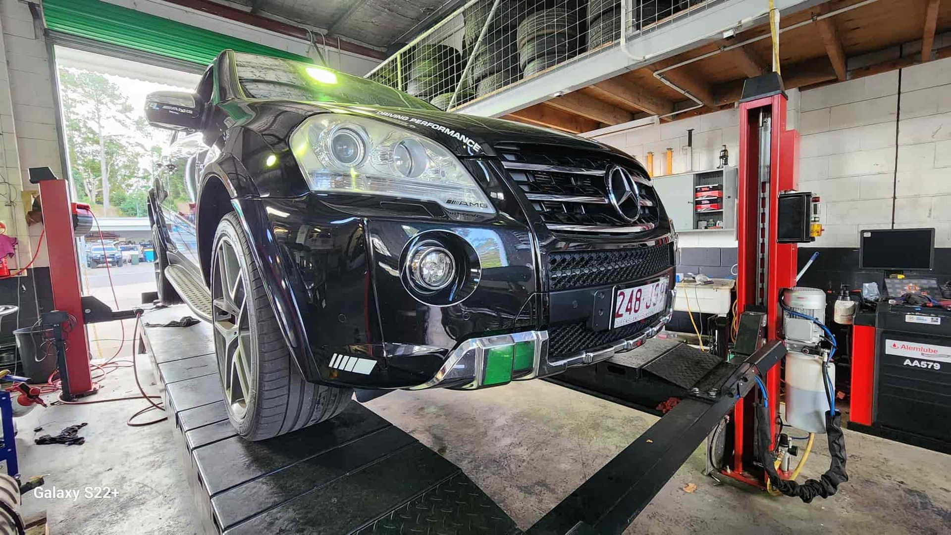 A Black Mercedes Benz is Sitting on a Lift in a Garage — Ultra Tune Nambour In Nambour, QLD