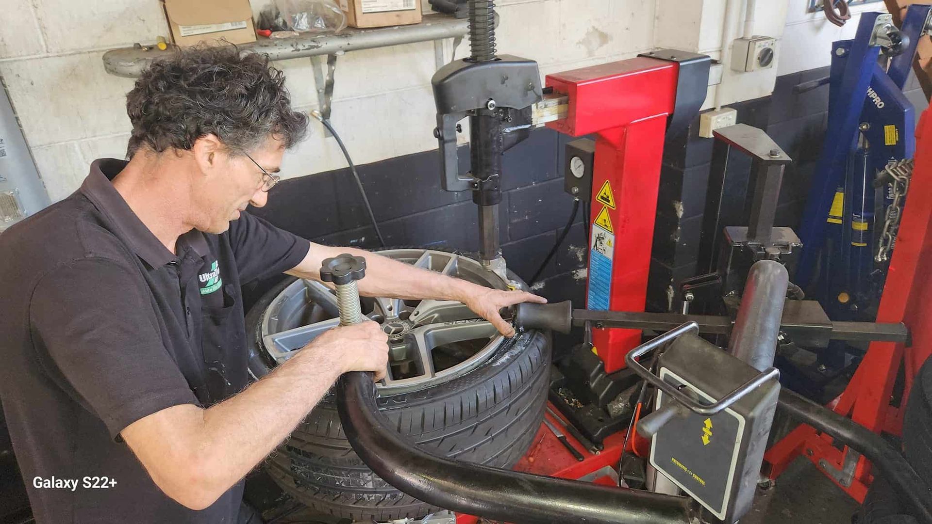 A Man is Working on a Tire on a Machine in a Garage — Ultra Tune Nambour In Nambour, QLD