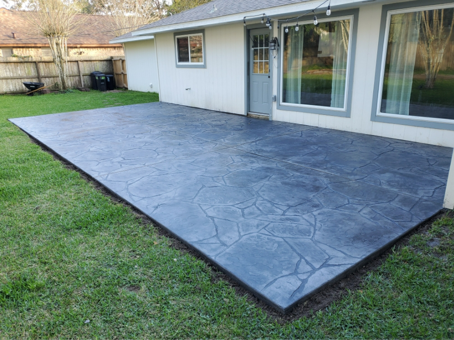 A large concrete patio is in the backyard of a house.