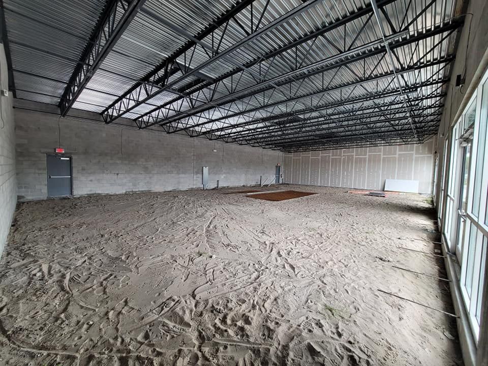 A large empty warehouse with a lot of dirt on the floor.