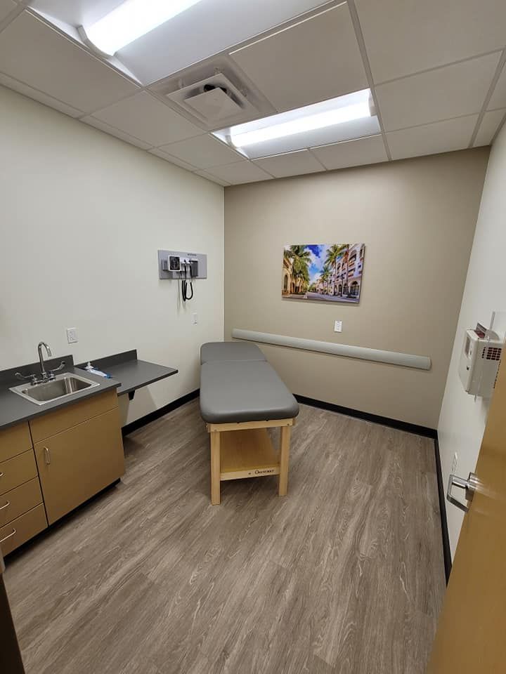A doctor 's office with a table and a sink.