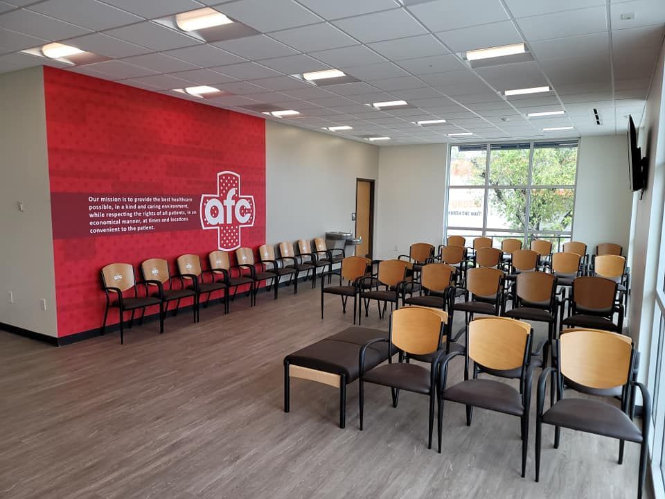 A waiting room with rows of chairs and a red wall.
