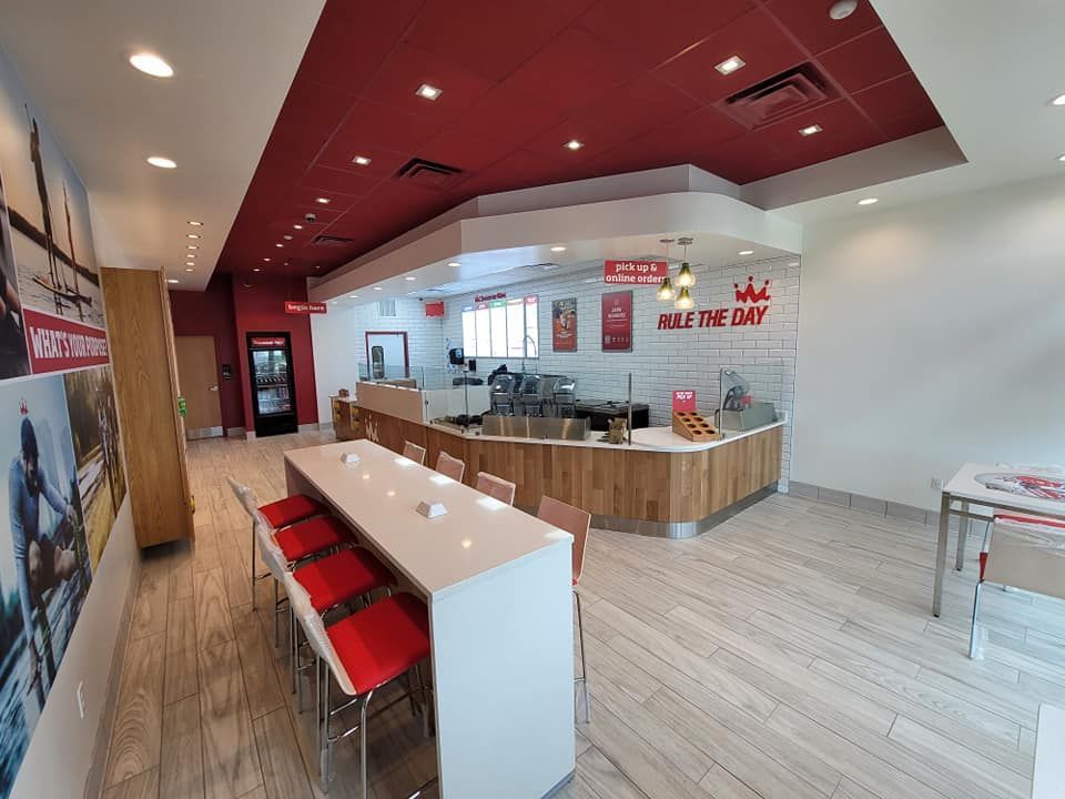 A restaurant with a long table and chairs and a red ceiling.