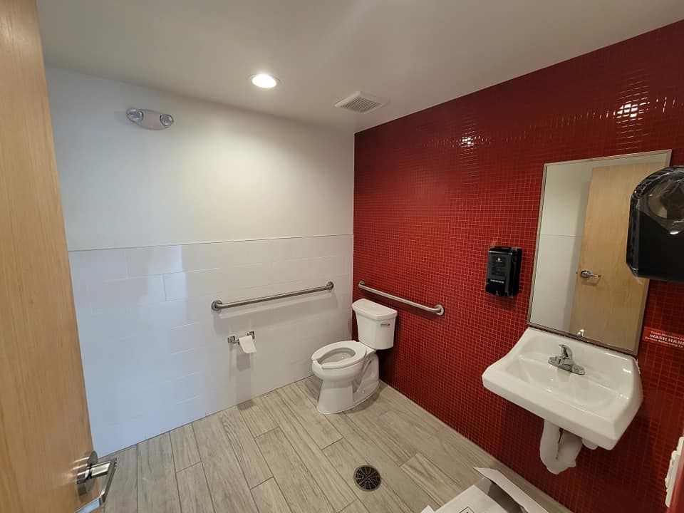 A bathroom with a toilet , sink and mirror.