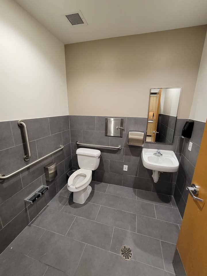 A bathroom with a toilet , sink and mirror.