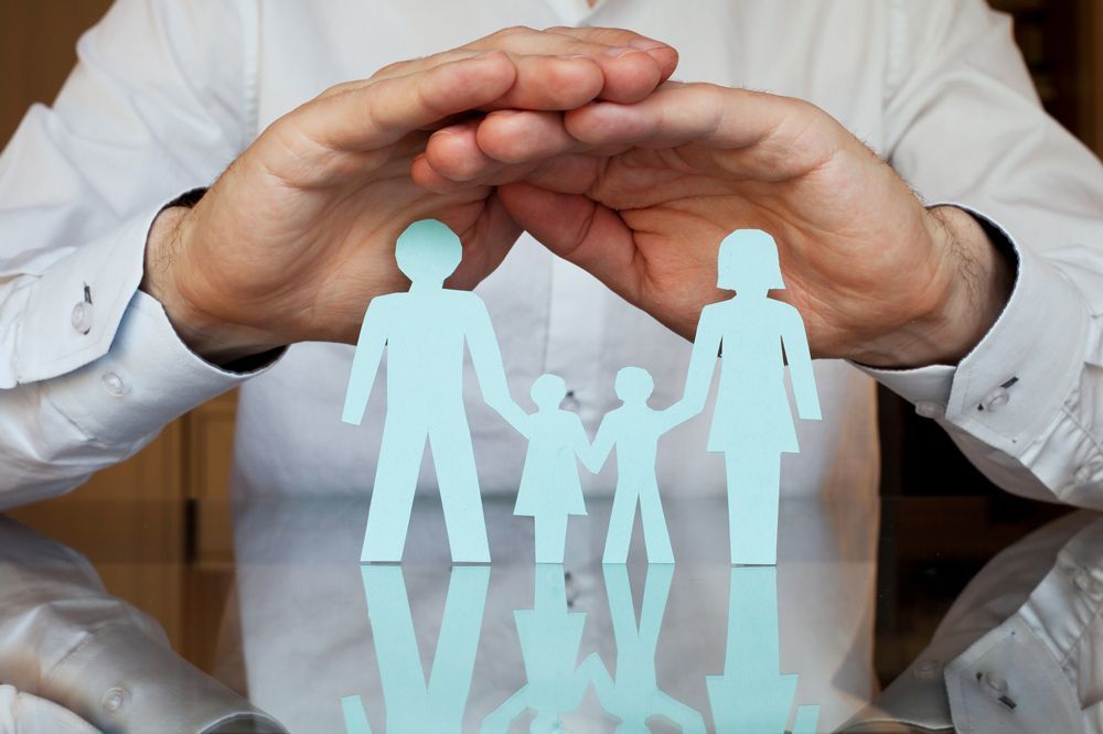 A man lifts paper cutouts of a family, reflecting the mission of McClure Insurance Agency and Brightstar Insurance in safeguarding families.