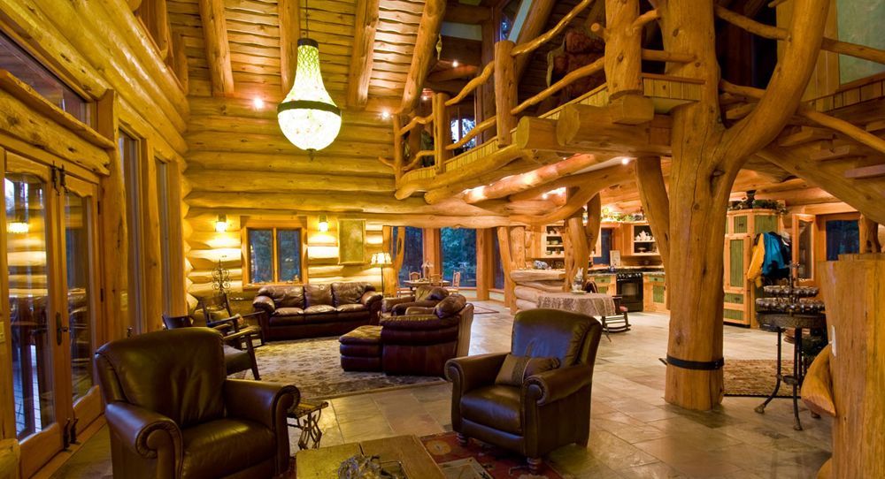 A living room in a log cabin with leather chairs and a couch on Chilko Lake, Canada.