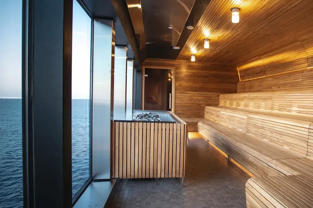 A wooden sauna with a large window overlooking the ocean on Hurtigruten Expeditions' MS Roald Amundsen cruise ship.