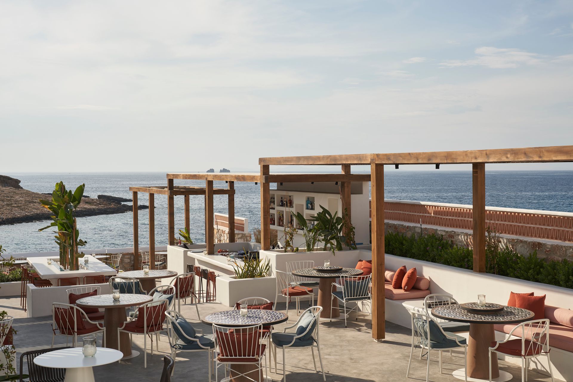 A restaurant with tables and chairs overlooking the ocean at Andronis Minois Hotel in Paros, Greece.