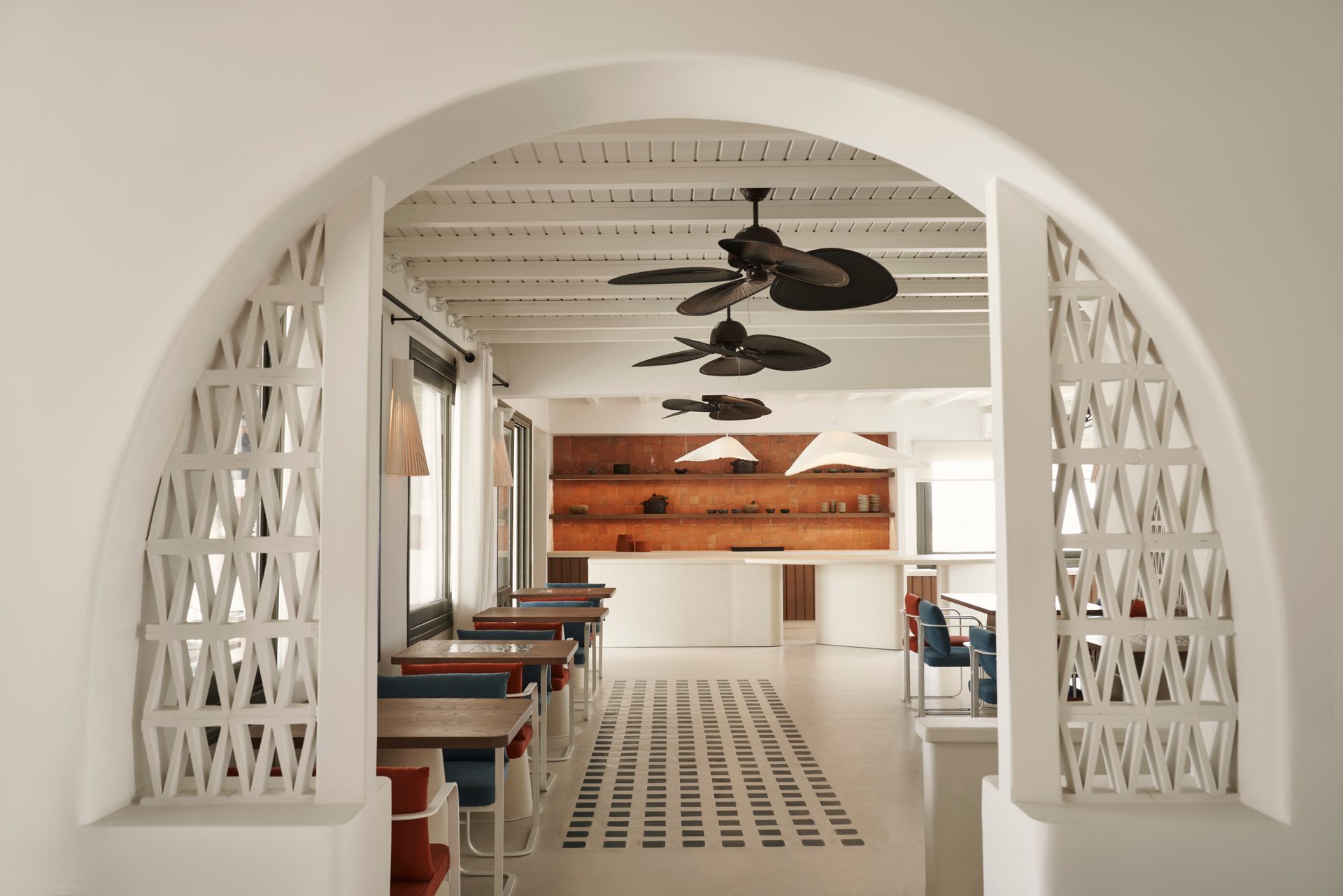 A room with tables and chairs and ceiling fans at Andronis Minois Hotel in Paros, Greece.