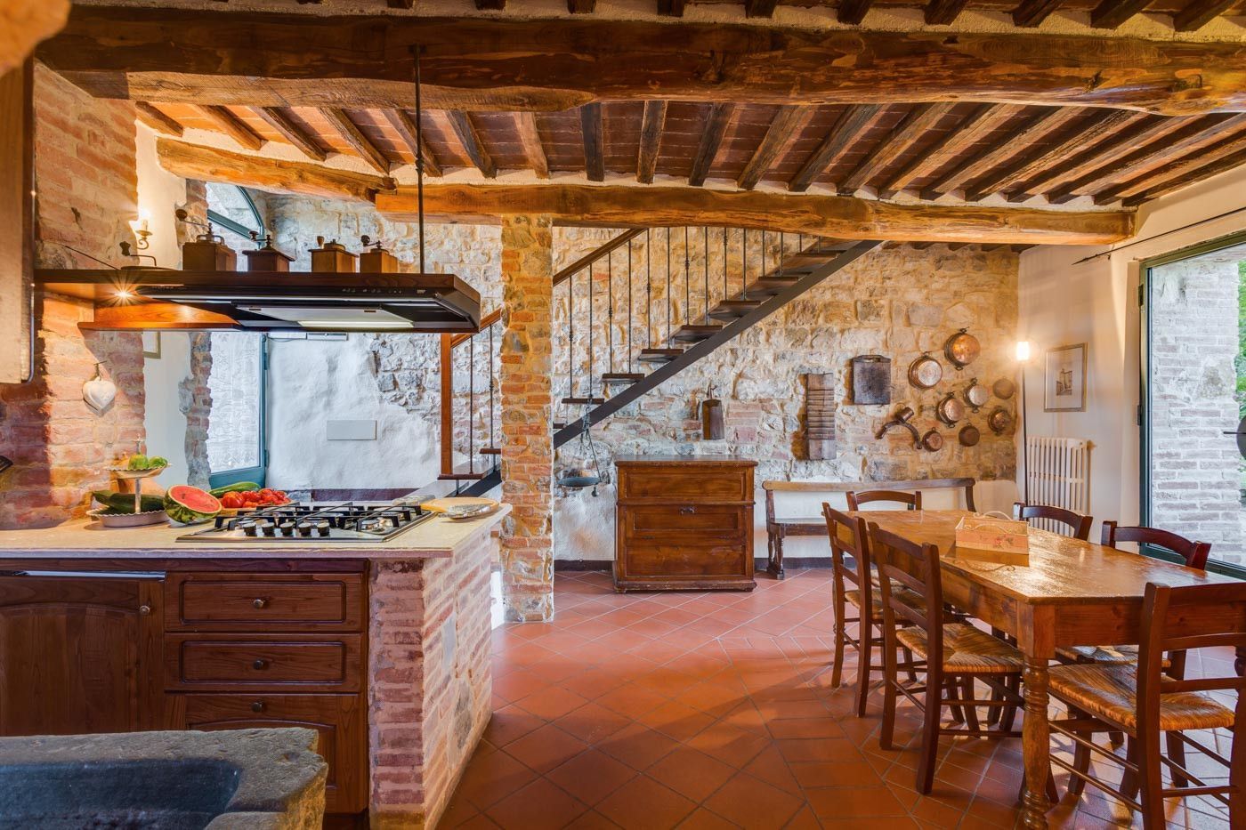 A kitchen with a table and chairs and a staircase in the background at villa in Tuscany.