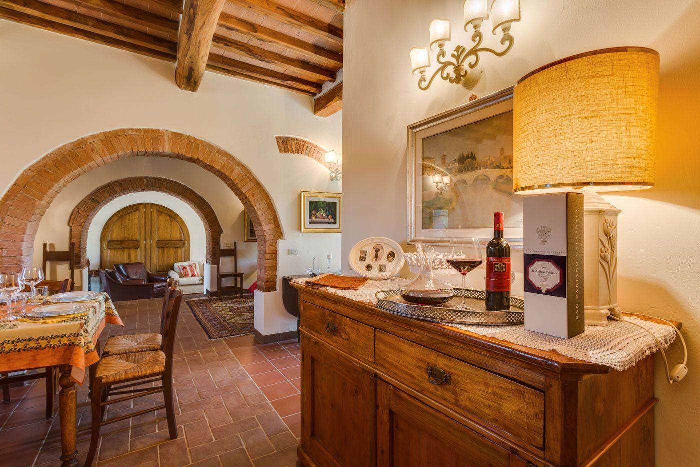 A wooden dresser with a bottle of wine on top of it in a living room at villa in Tuscany.