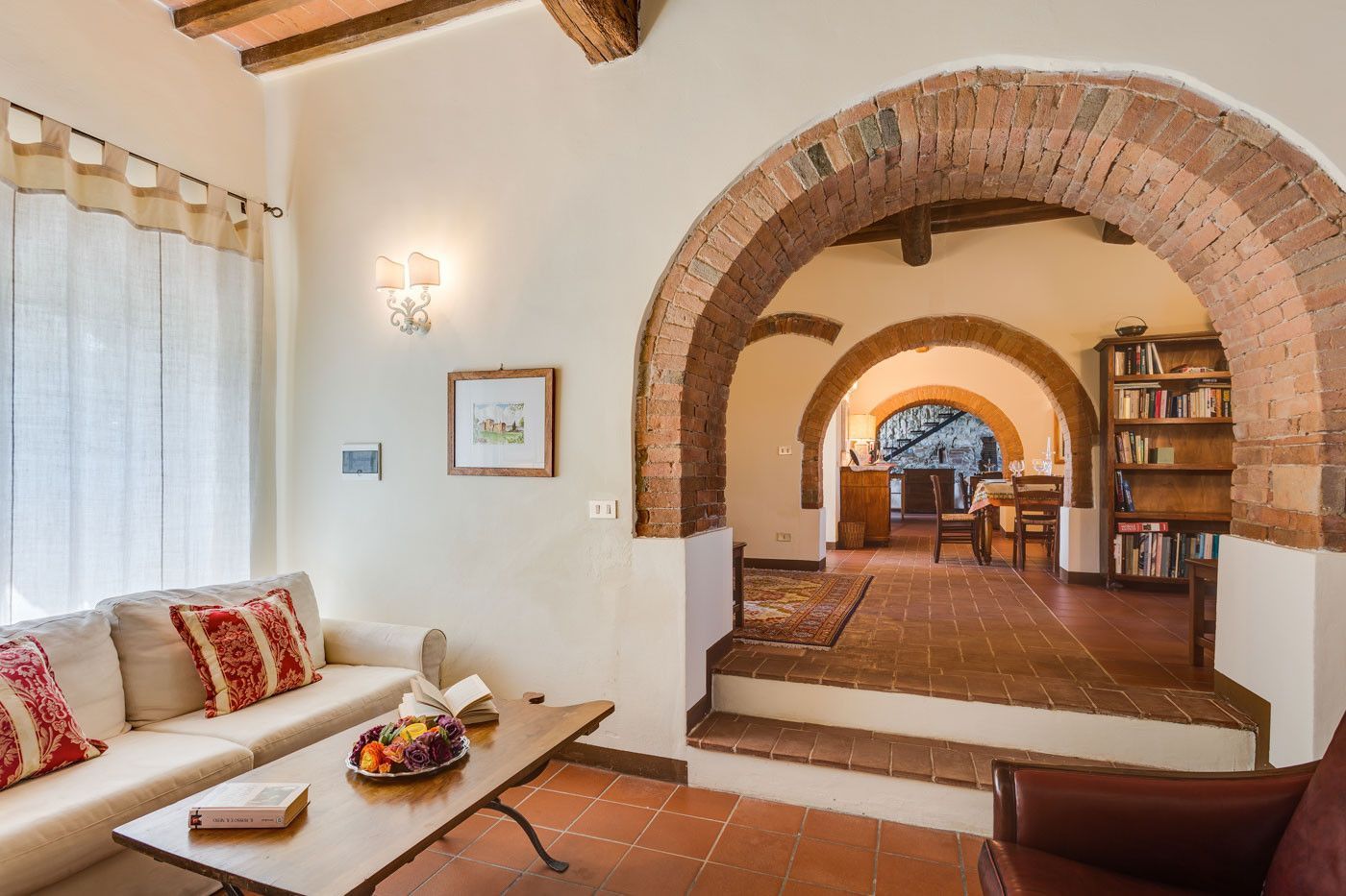 A living room with a brick archway and a couch and chair at villa in Tuscany.