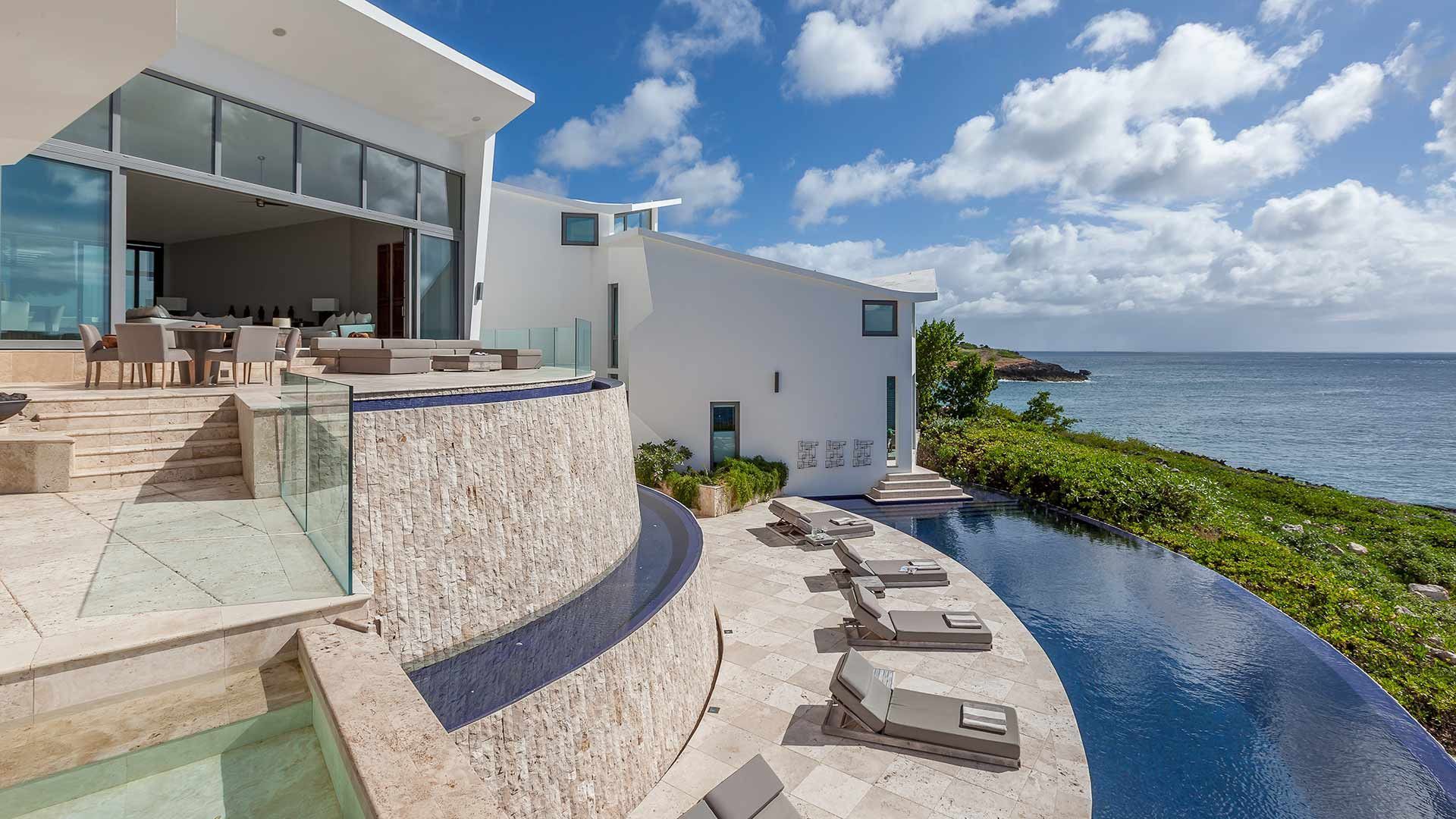 A large white villa with a swimming pool and a view of the ocean in Antigua.