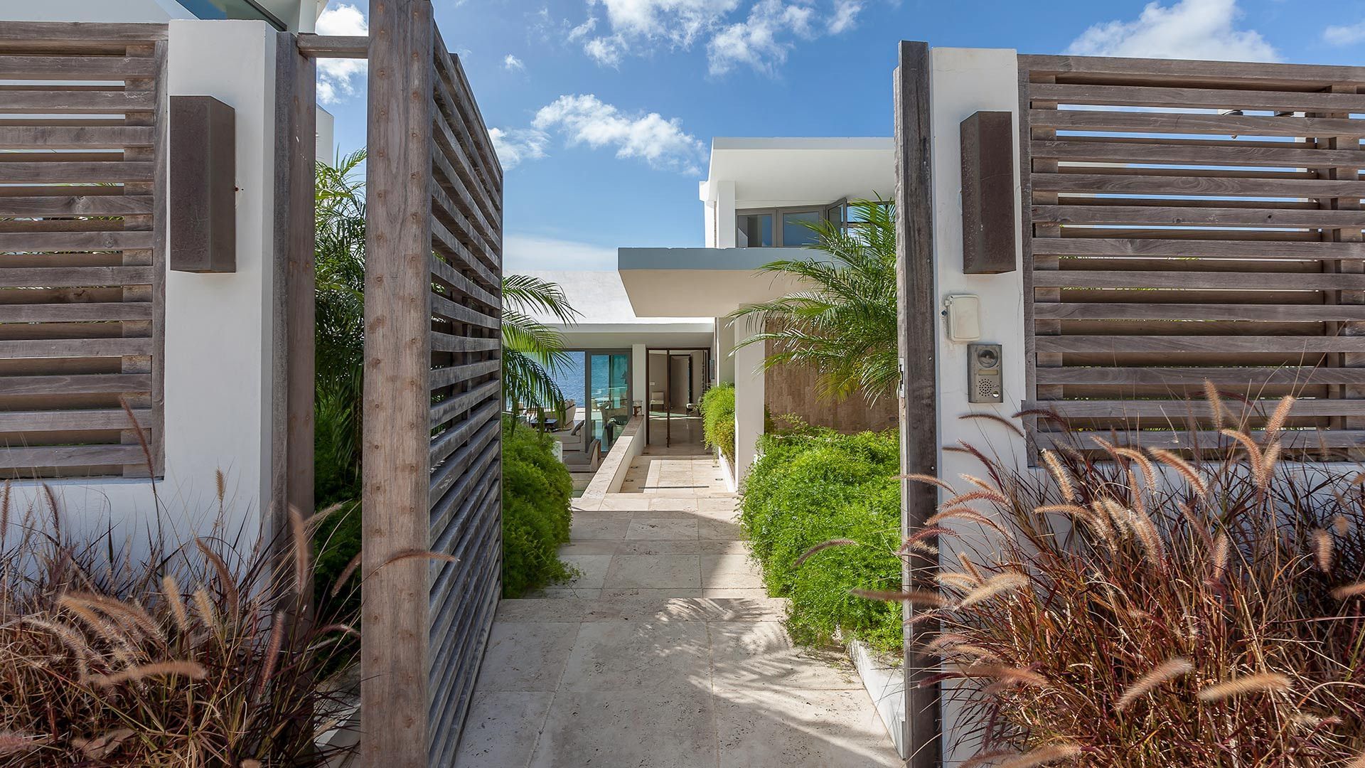 The entrance to a villa with a wooden gate and a walkway leading to it in Antigua.