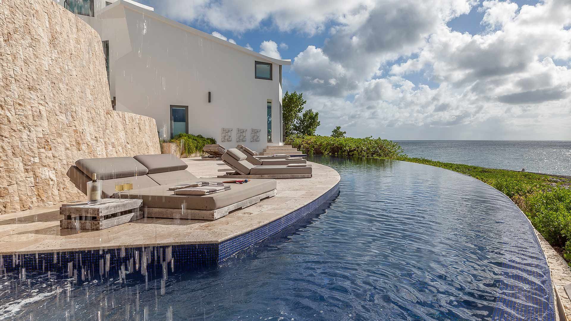 A swimming pool with a view of the ocean and a white villa in the background in Antigua.