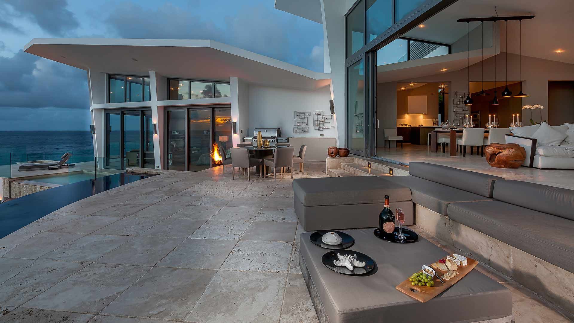 A living room with a couch and a table with a view of the ocean at villa in Antigua.