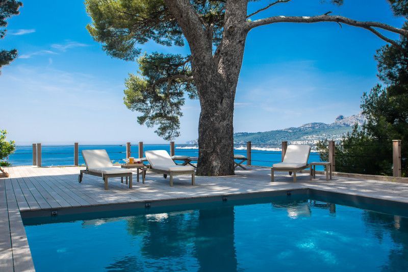 There is a swimming pool with chairs around it and a view of the ocean at villa in Cote D'Azur, France.