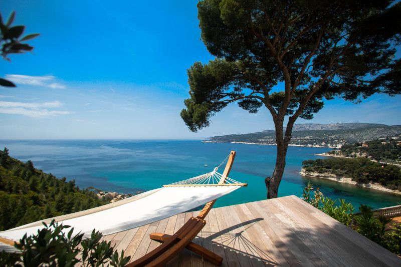 A hammock is sitting on a wooden deck overlooking the ocean at villa in Cote D'Azur, France.