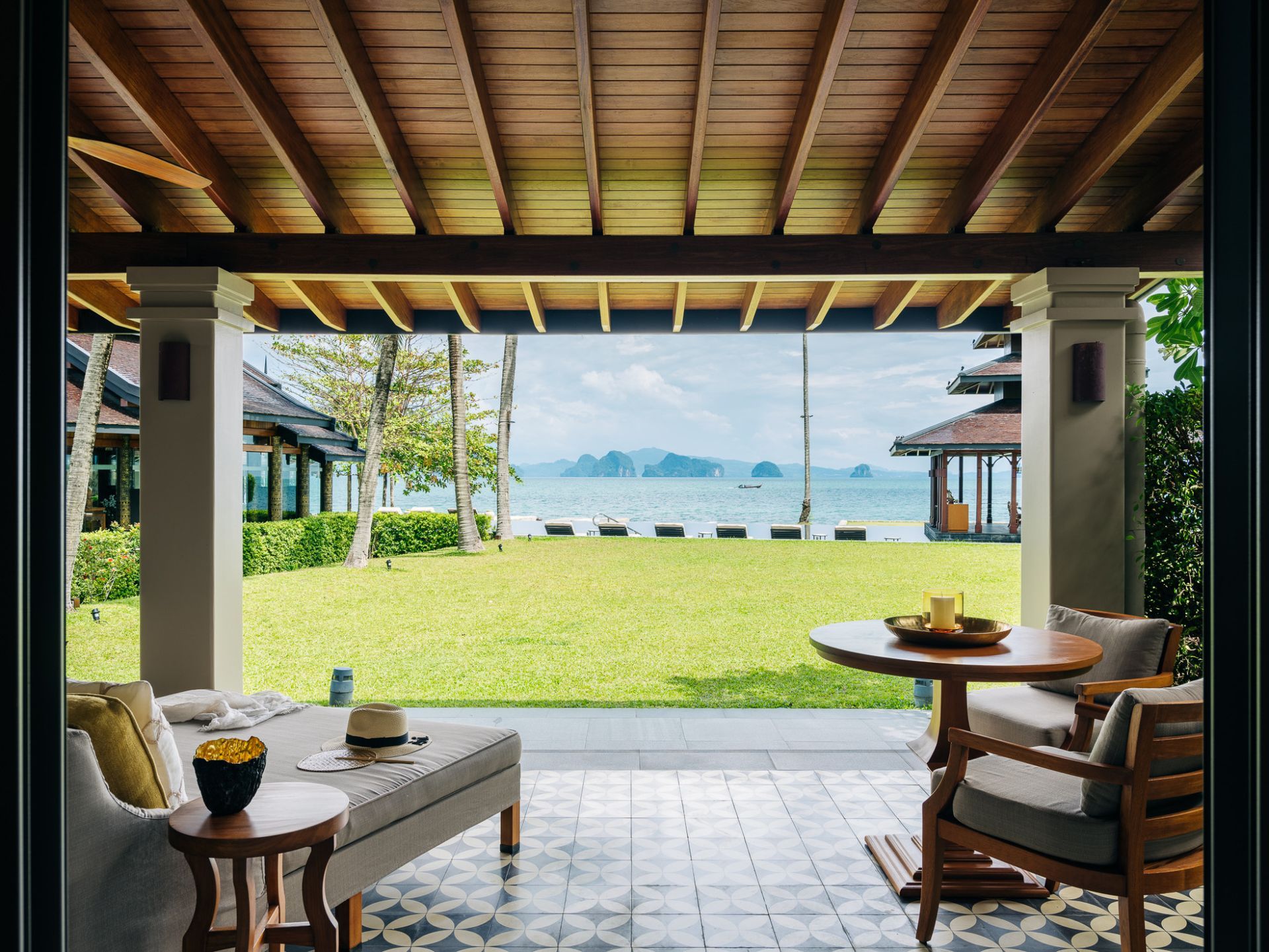 A patio with a table and chairs and a view of the ocean at villa in Koh Yao Noi, Thailand.