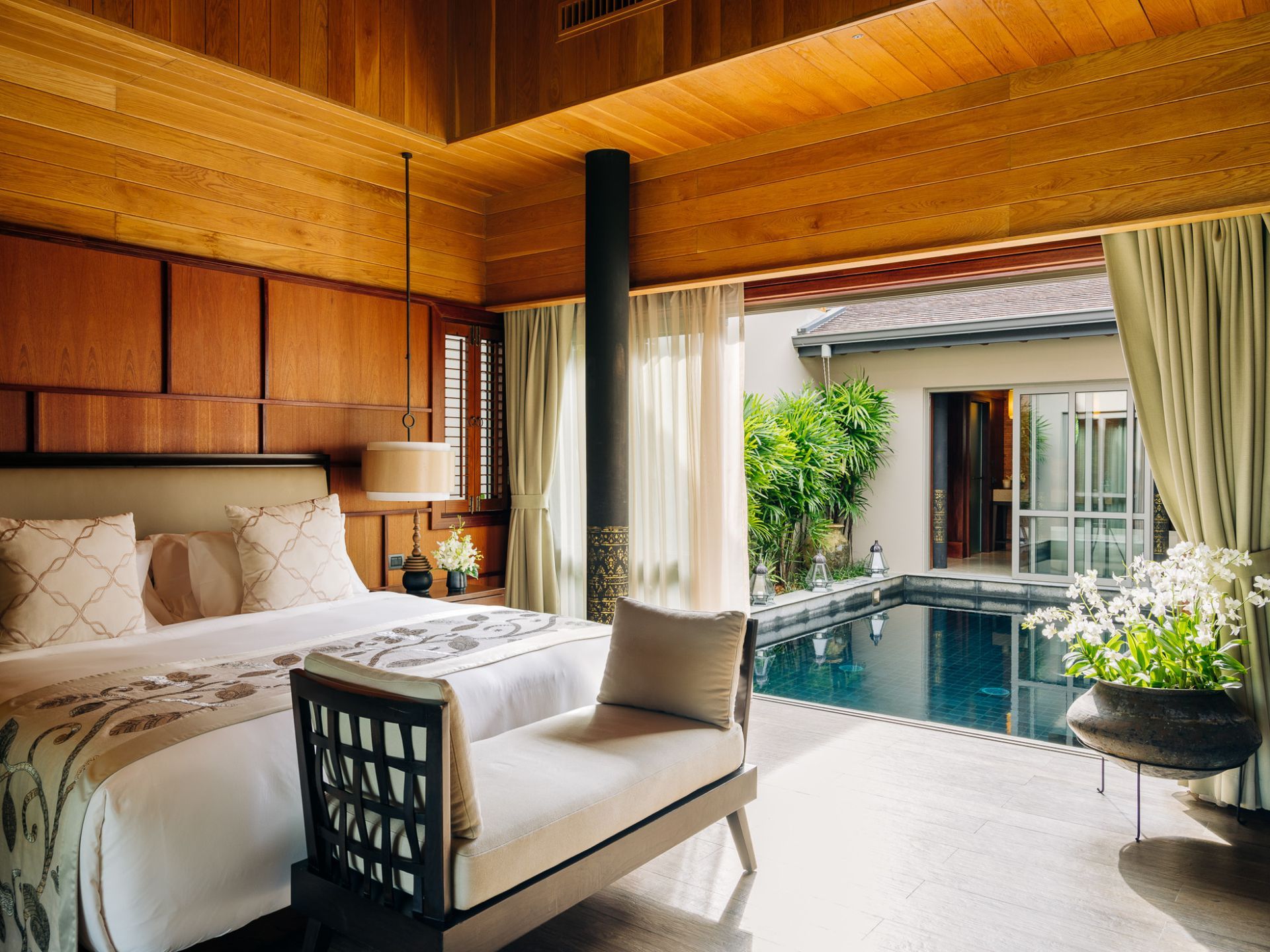 A bedroom with a bed , couch , and a swimming pool at villa in Koh Yao Noi, Thailand.