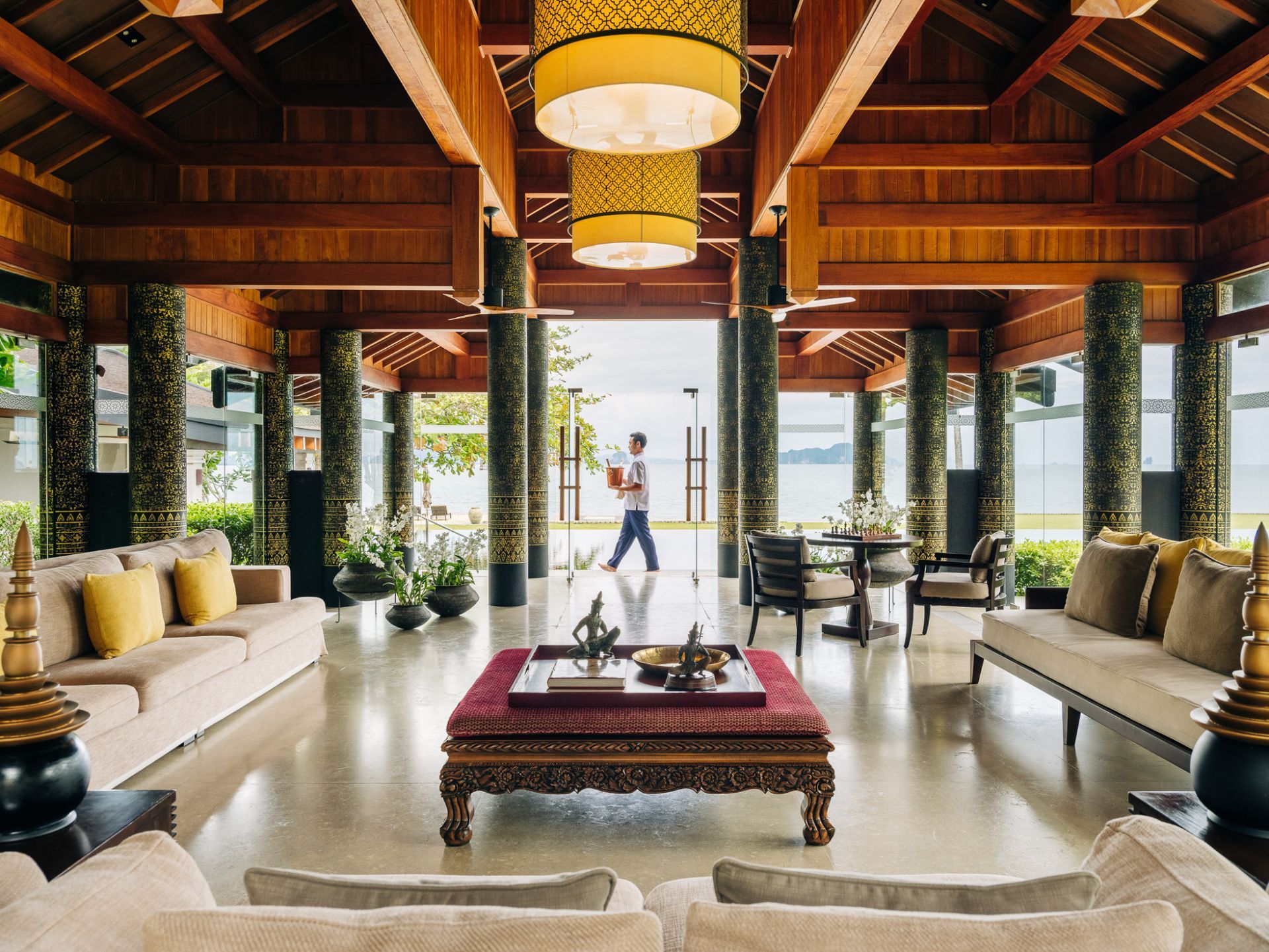 A living room filled with furniture and a man standing in the doorway at villa in Koh Yao Noi, Thailand.