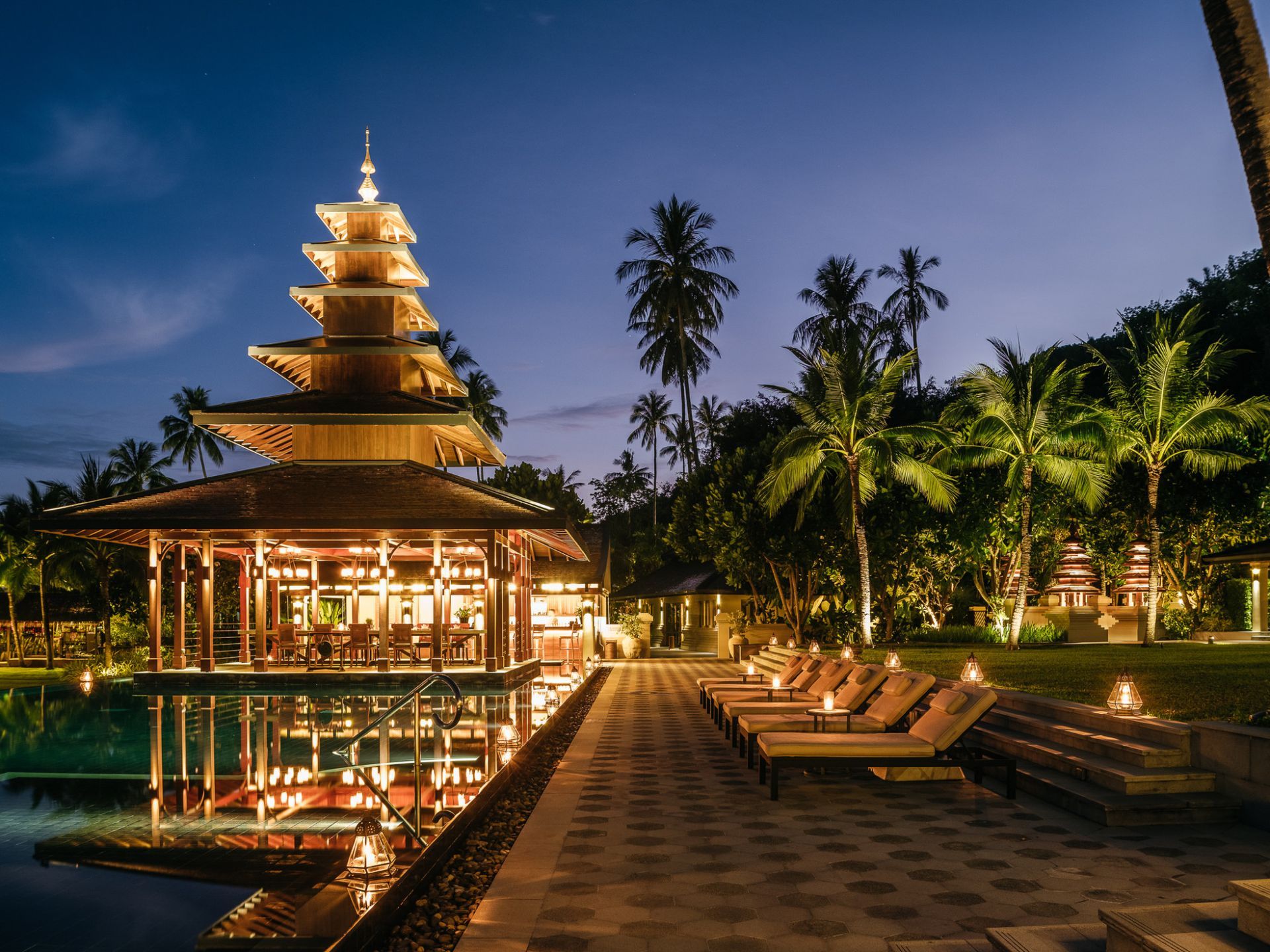 A swimming pool with a pagoda villa in the middle of it at night in Koh Yao Noi, Thailand.