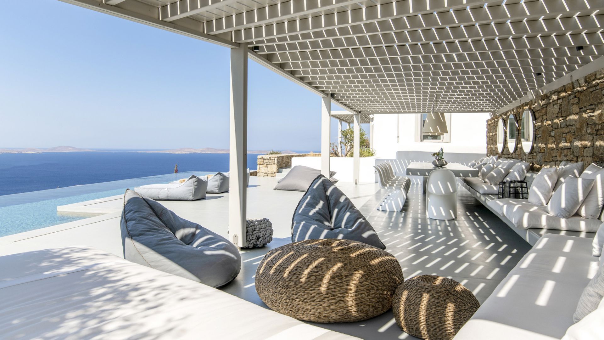 A patio with a view of the ocean and a swimming pool at villa in Mykonos, Greece.