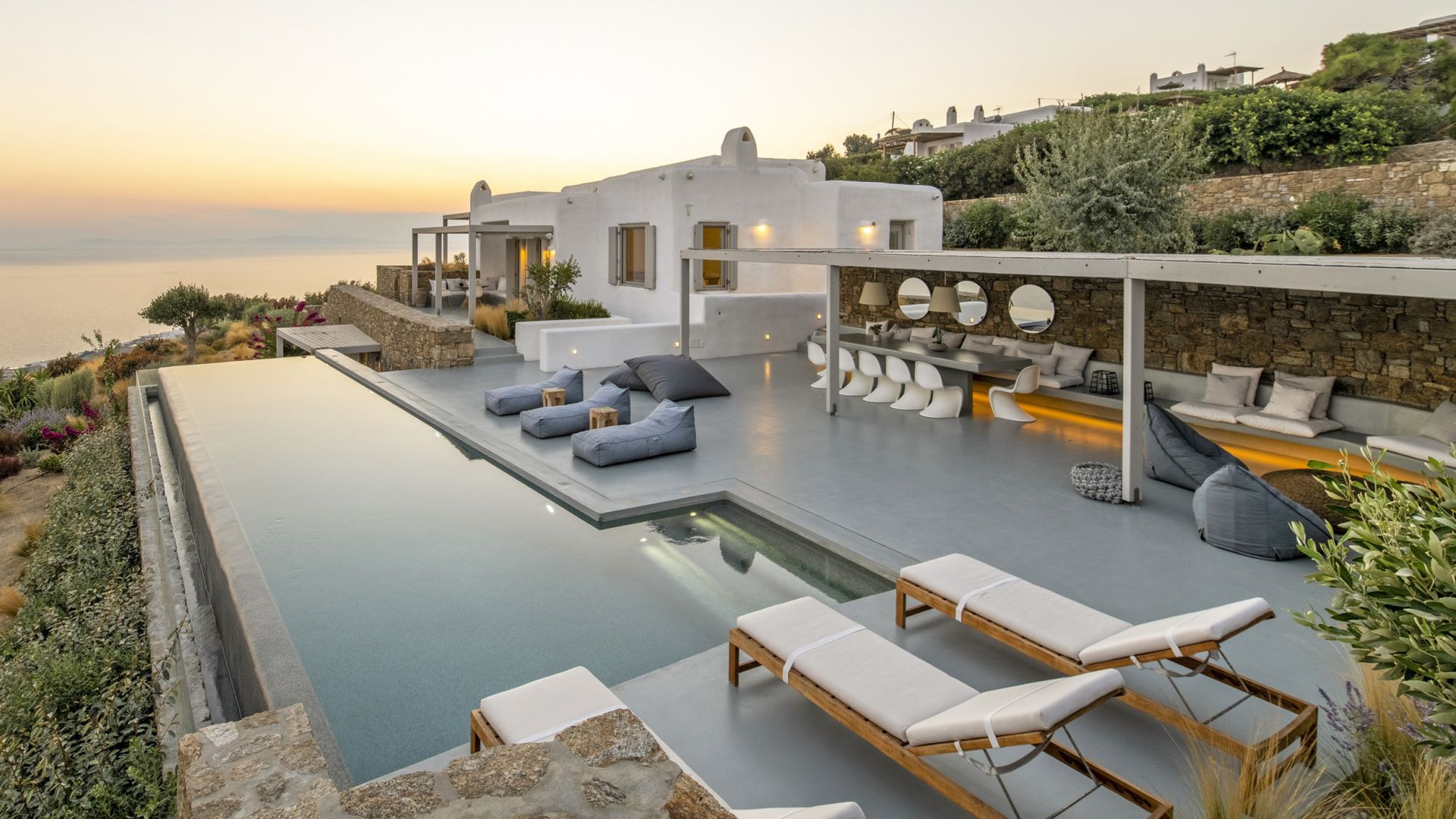 There is a large swimming pool in front of a villa in Mykonos, Greece