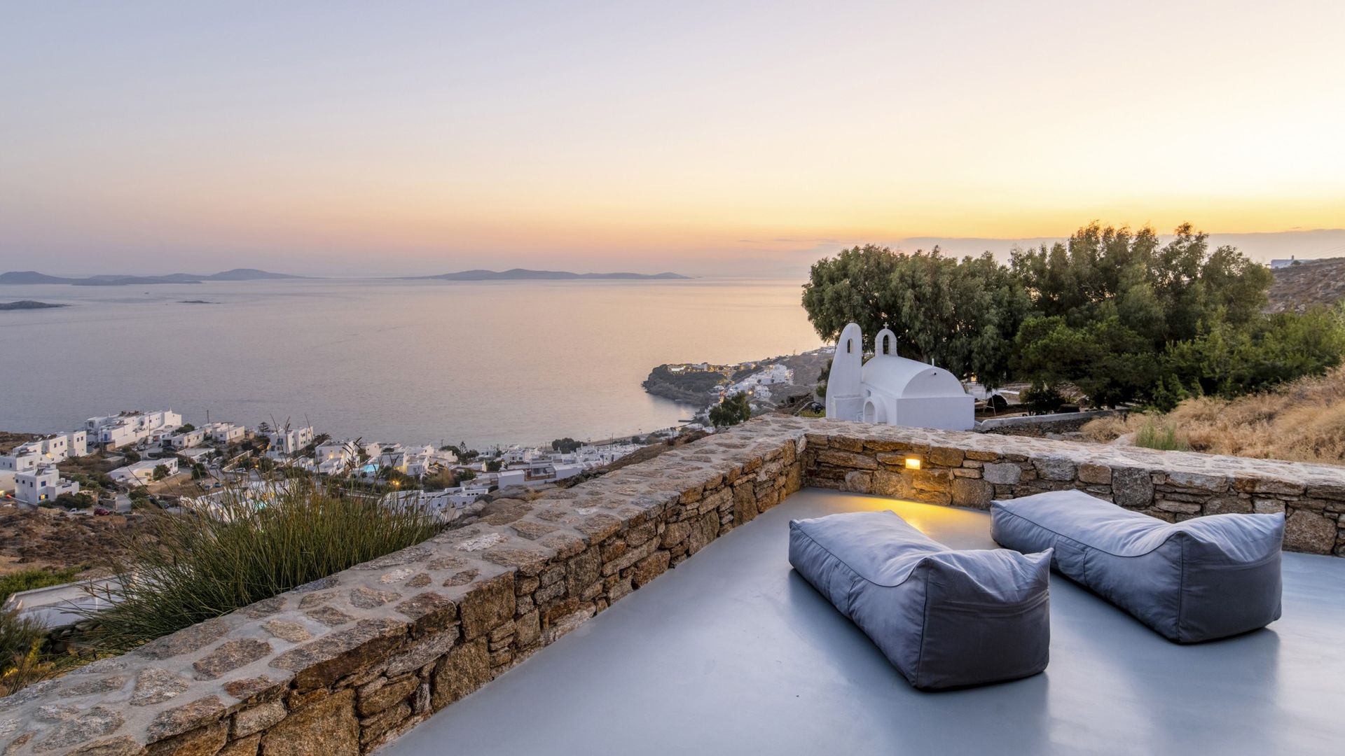 A patio with a view of the ocean and a stone wall in at villa Mykonos, Greece.