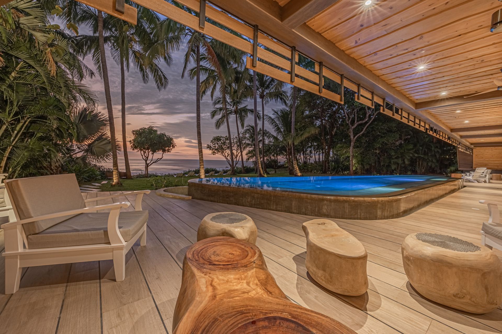 A wooden deck with chairs and tables next to a swimming pool.