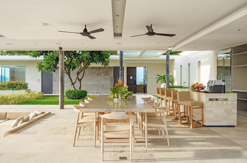 A dining room with a long table and chairs and ceiling fans at villa in Koh Samui, Thailand.