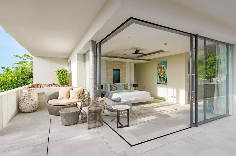 A bedroom with a large bed and a balcony with sliding glass doors at villa in Koh Samui, Thailand.