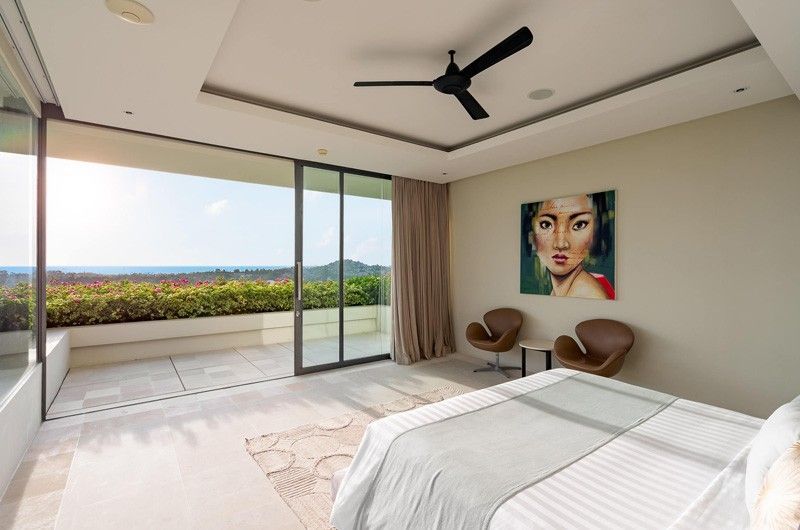 A bedroom with a bed, chairs and a painting on the wall at villa in Koh Samui, Thailand.