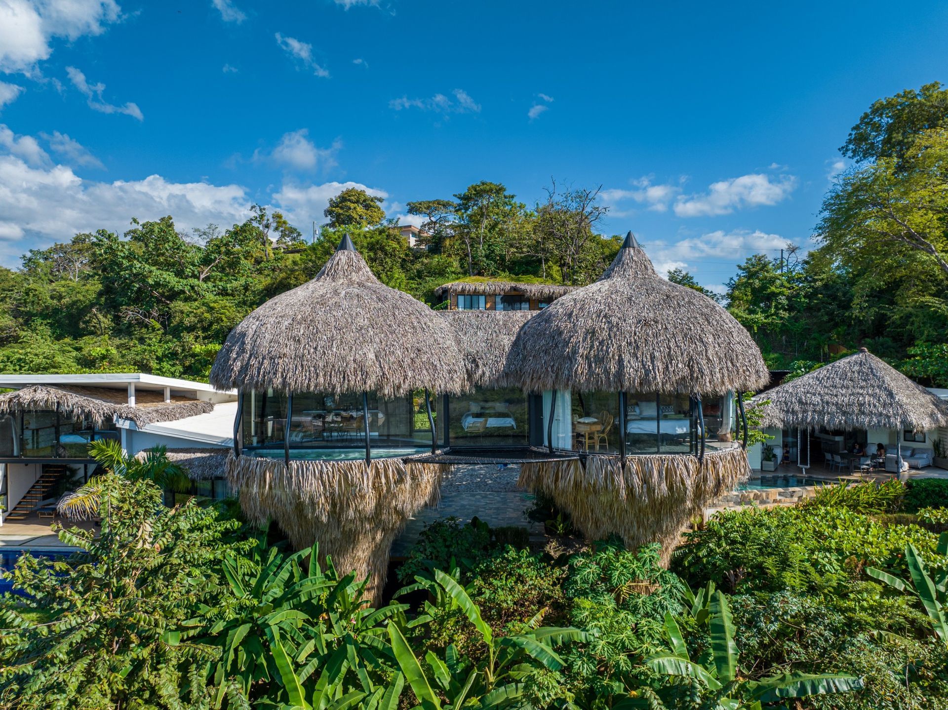 A large villa with thatched roofs is surrounded by trees and bushes in Costa Rica.