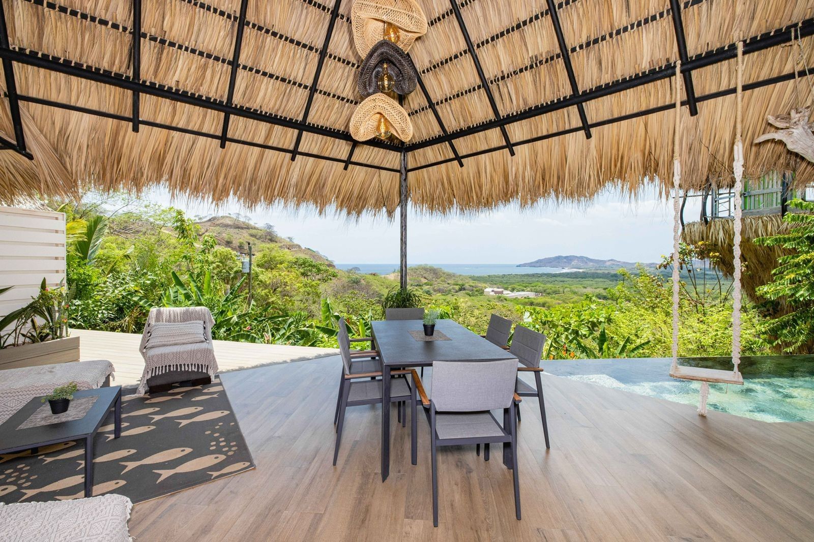 There is a table and chairs under a thatched roof at villa in Costa Rica.