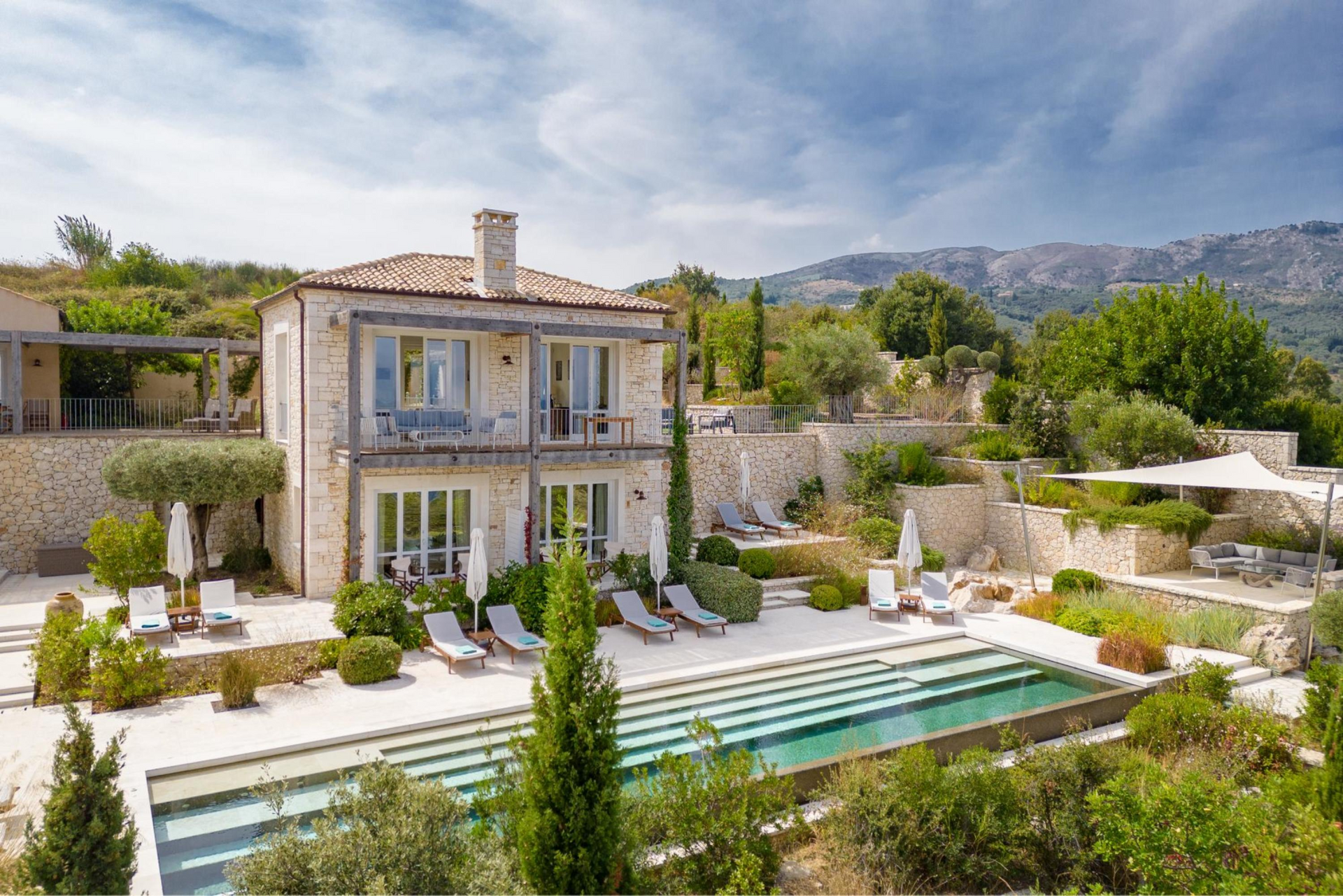 An aerial view of a villa with a swimming pool in front of it in Corfu, Greece.