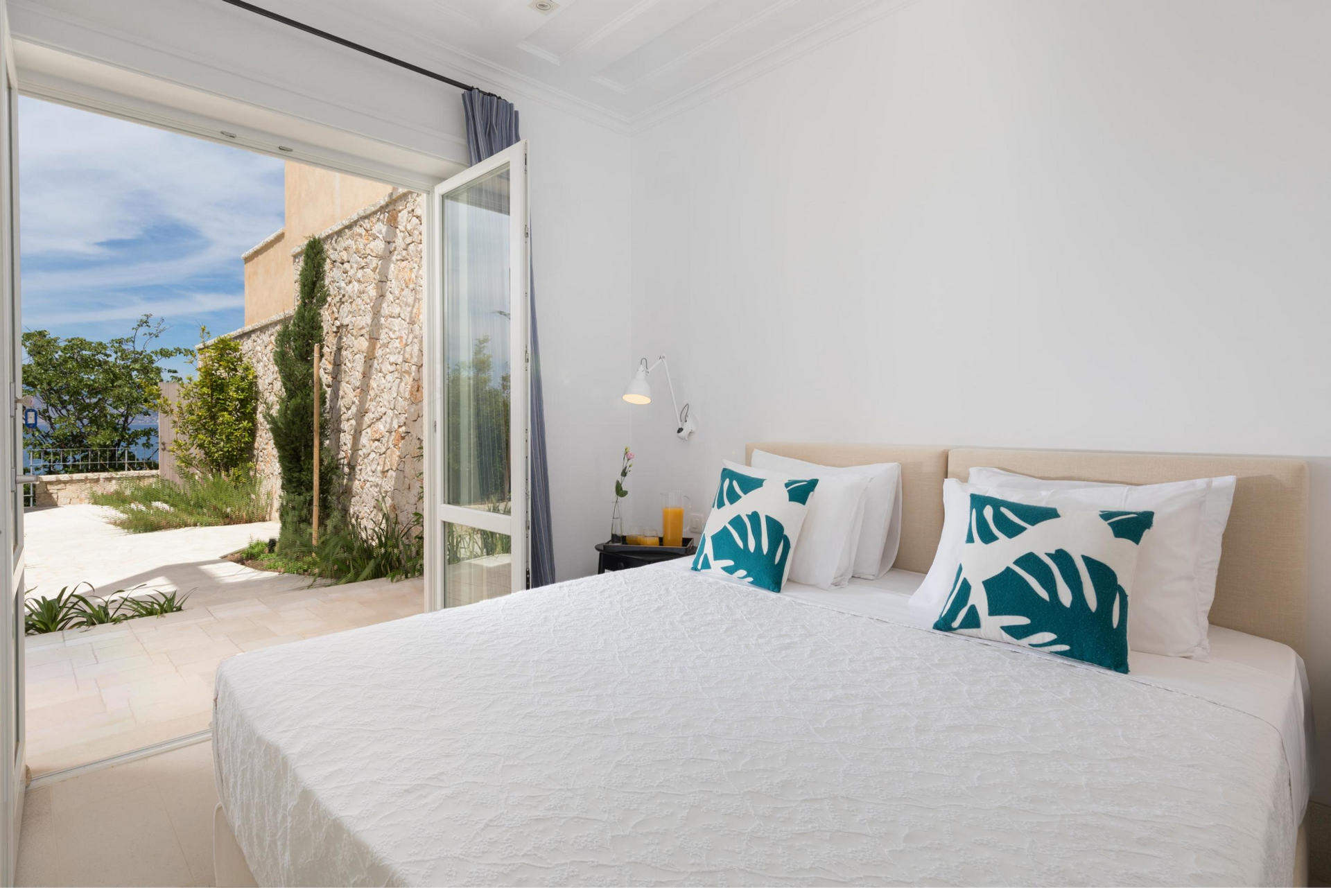 A bedroom with a large bed and a sliding glass door leading to a patio at villa in Corfu, Greece.