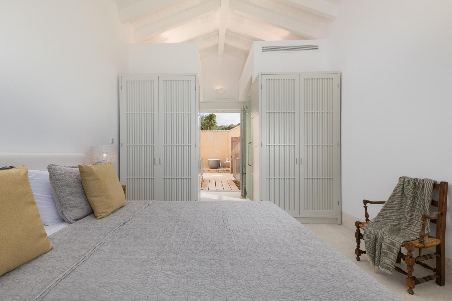 A bedroom with a large bed and a chair at villa in Corfu, Greece.