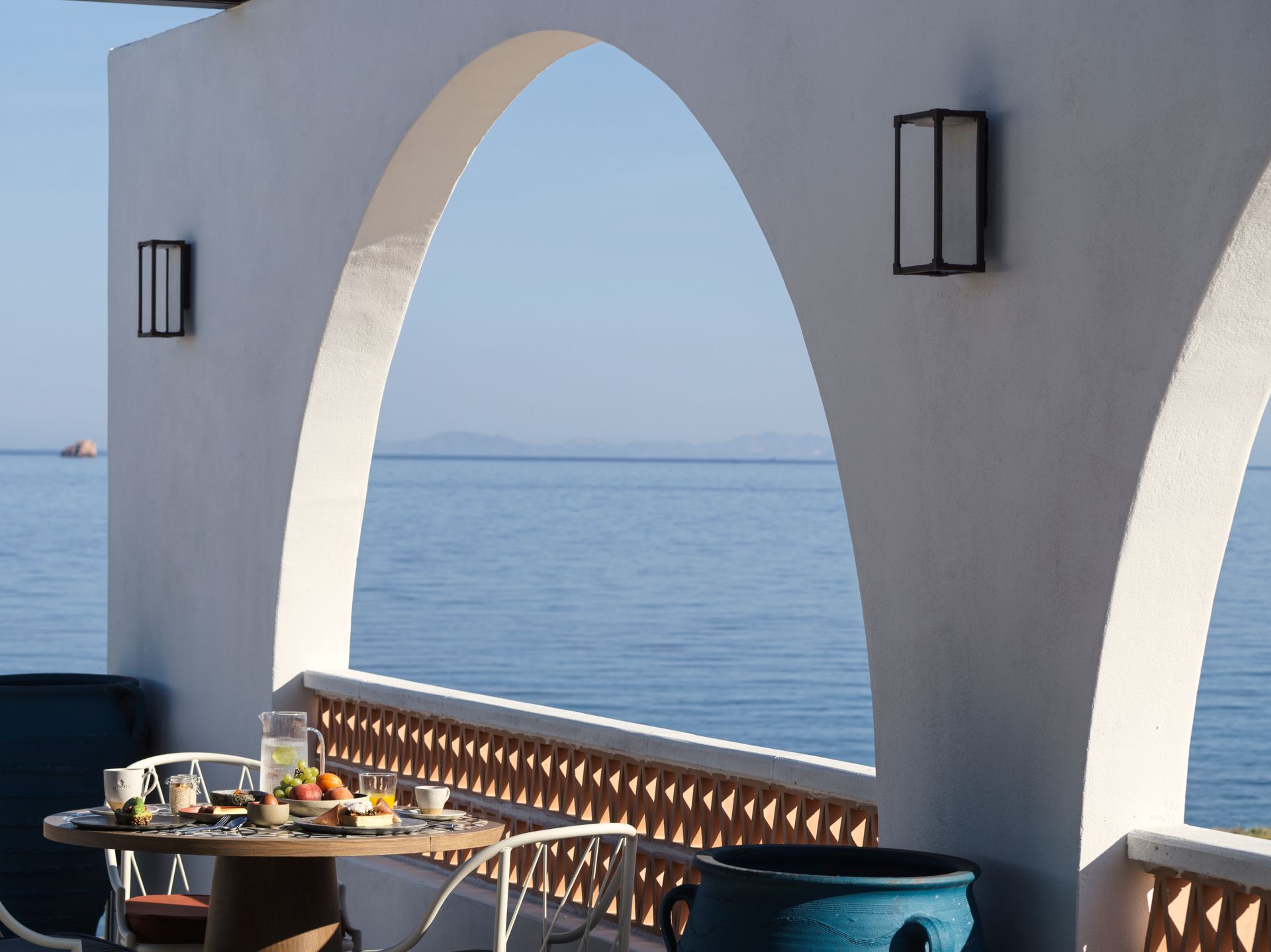 A table and chairs on a balcony overlooking the ocean at Andronis Minois Hotel in Paros, Greece.