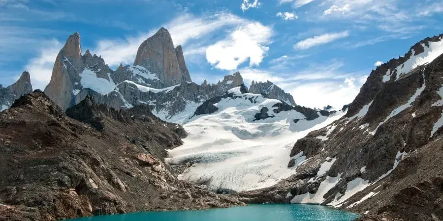 A lake surrounded by snow-covered mountains with a blue sky in the background in Patagonia.