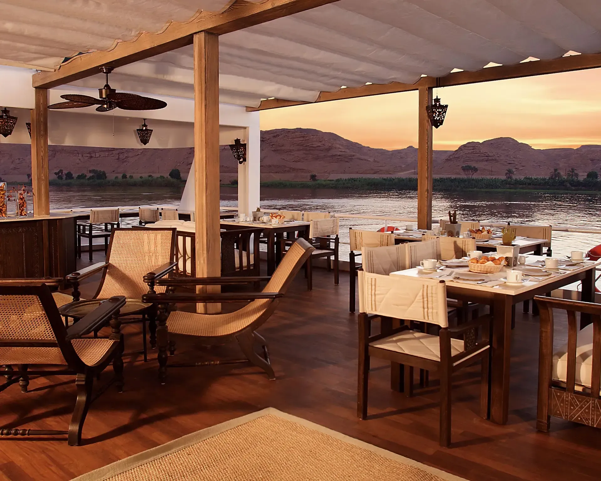 A restaurant with tables and chairs overlooking a body of water on Abercrombie & Kent's Sun Boat III.