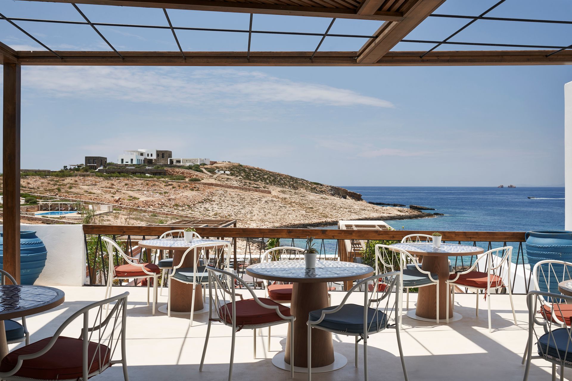 A restaurant with tables and chairs overlooking the ocean at Andronis Minois Hotel in Paros, Greece.