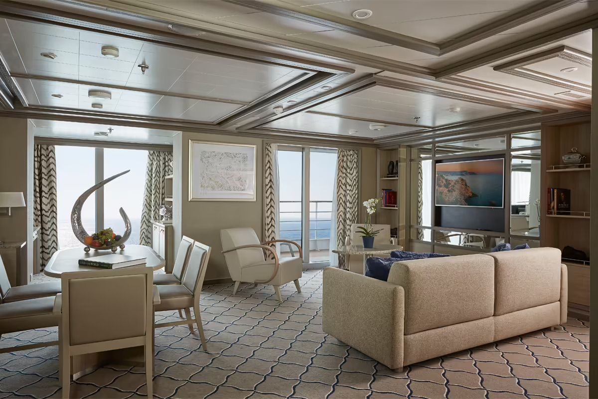 A living room with a couch , chairs , a table and a television on Silversea's Silver Muse cruise ship.