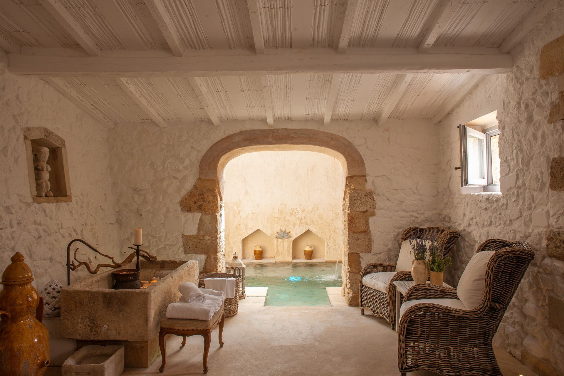 A room with a sink and chairs and a pool in the background at Naturalis Bio Resort & Spa in Puglia, Italy.