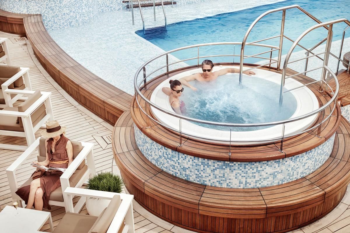 A man and a woman are sitting in a jacuzzi on Silversea's Silver Muse cruise ship.