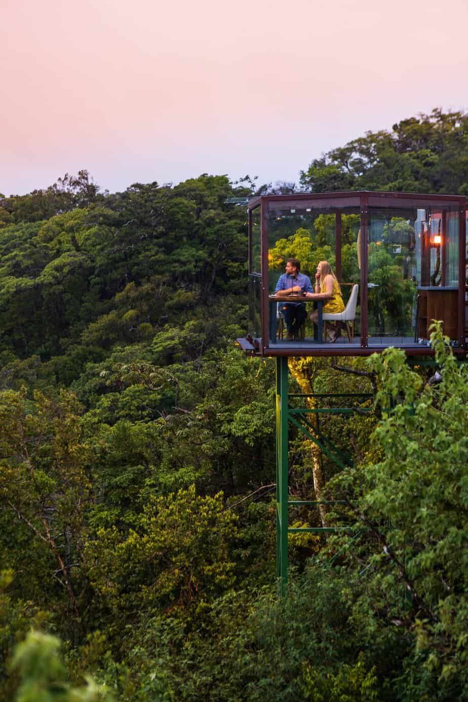 A couple is sitting at a table in the middle of a forest in costa rica.