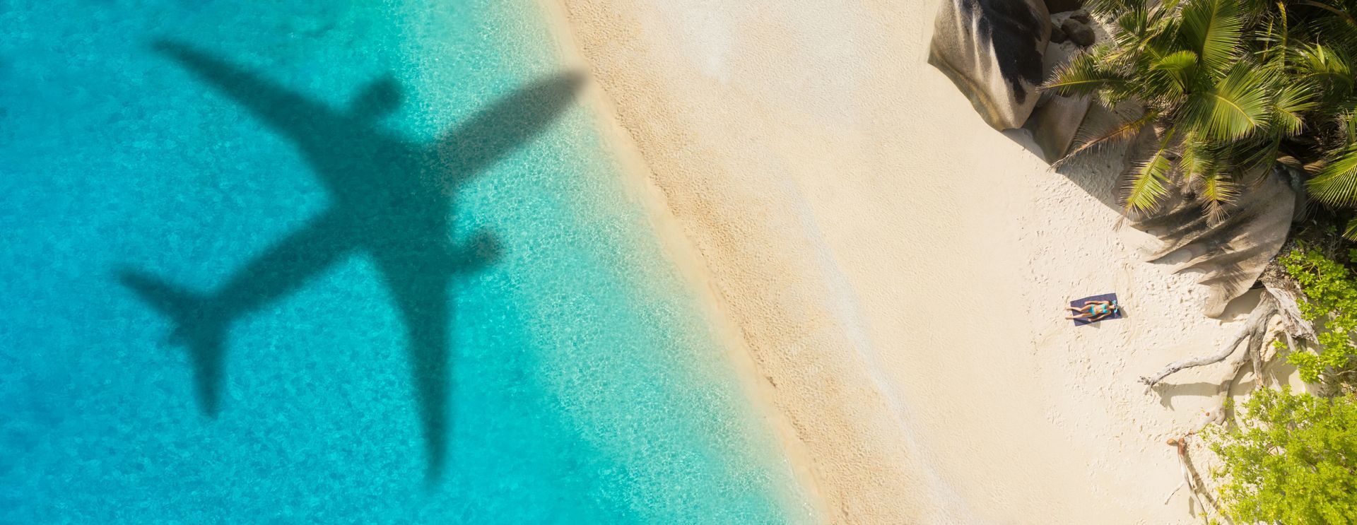 A plane is casting a shadow on a beach.