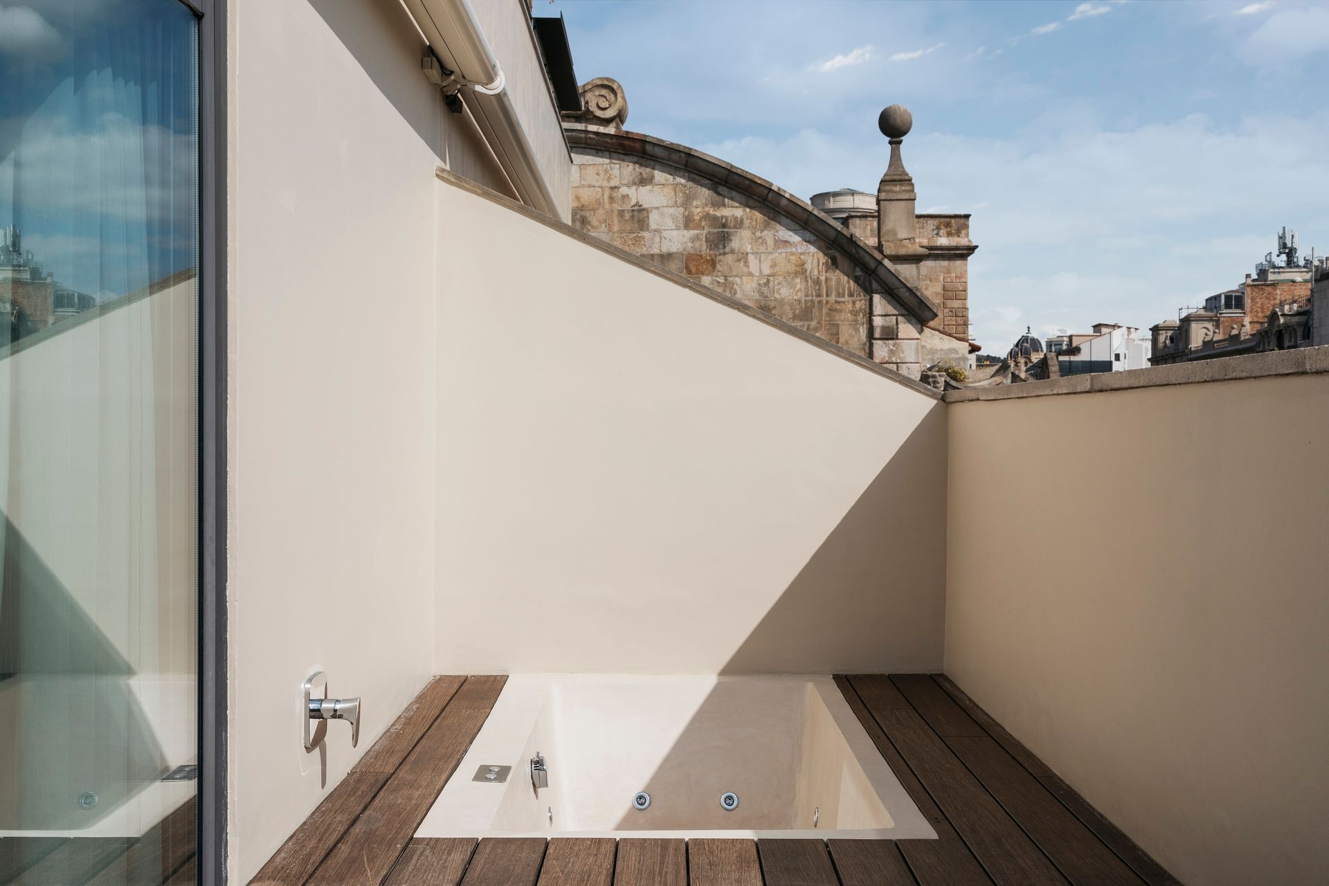 A jacuzzi tub is sitting on a wooden deck next to a window at Hotel Bagués in Barcelona, Spain